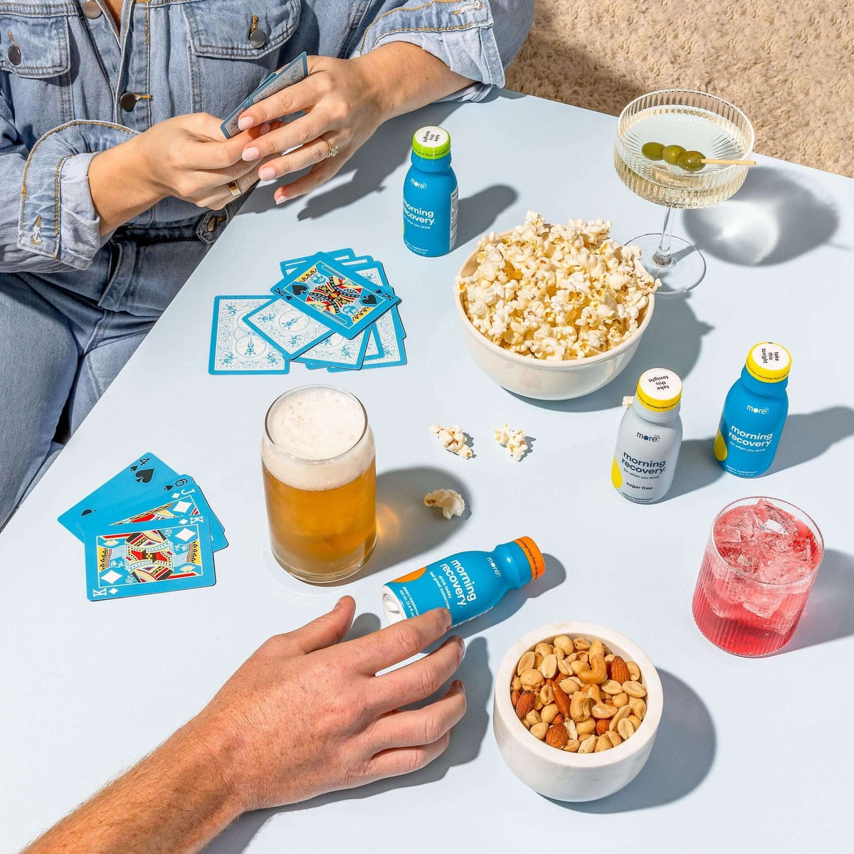 Enjoying snacks and drinks with Morning Recovery herbal supplements on a table during a fun gathering.